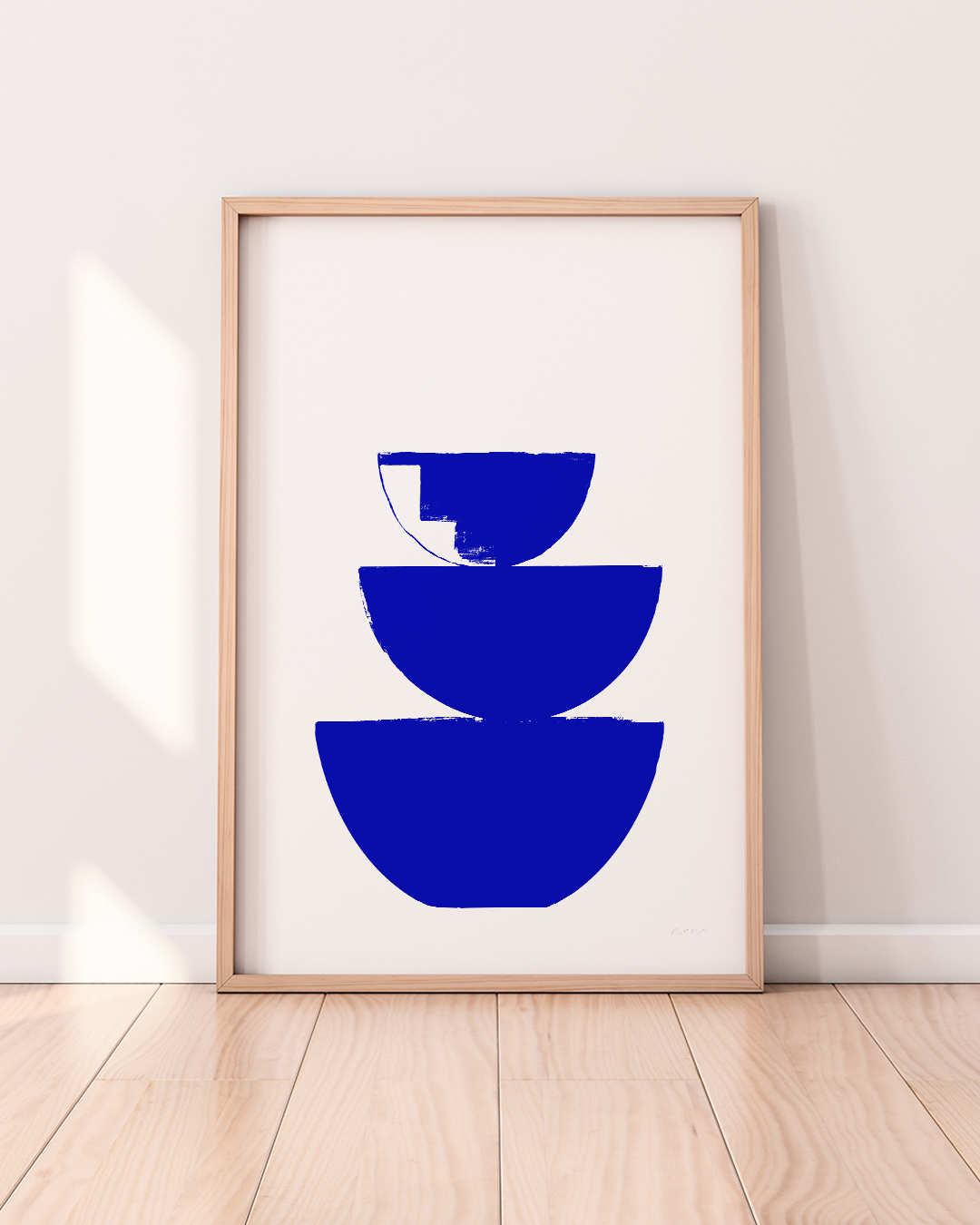 Stacked bowl silhouette artwork in cobalt blue, framed in white room