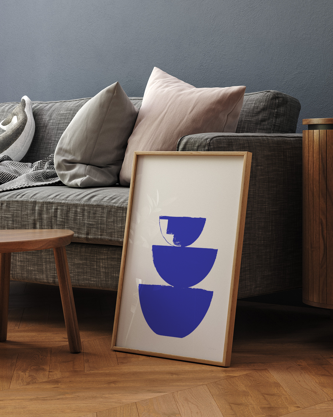 Blue Bowls Art Print leaning beside neutral-toned cushions on sofa