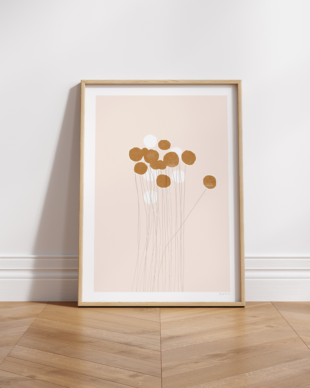Framed Pom-Pom print on white wall above a light wood shelf
